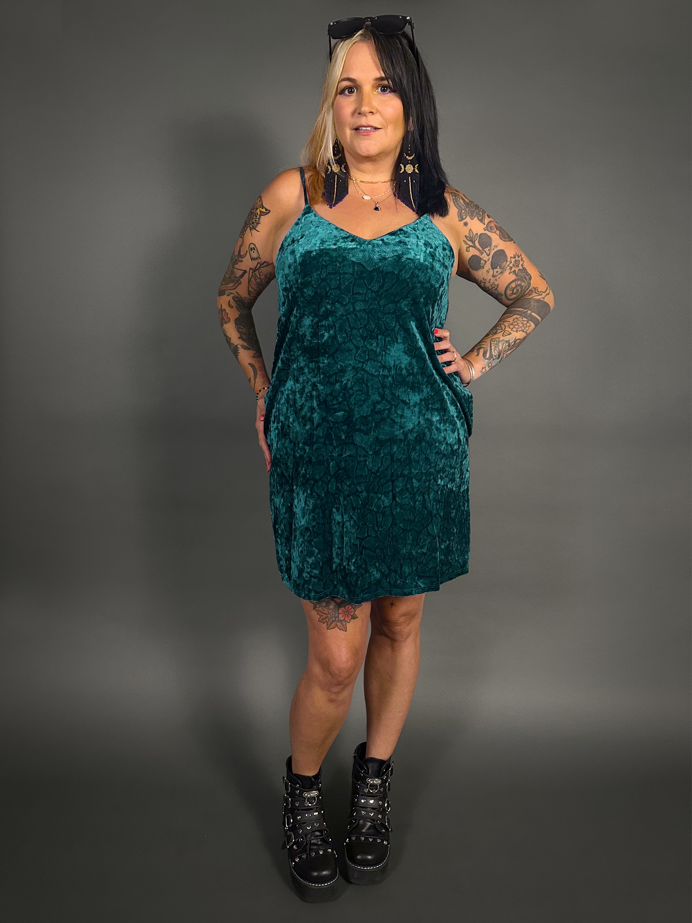 Woman wearing a teal velvet dress against a gray background