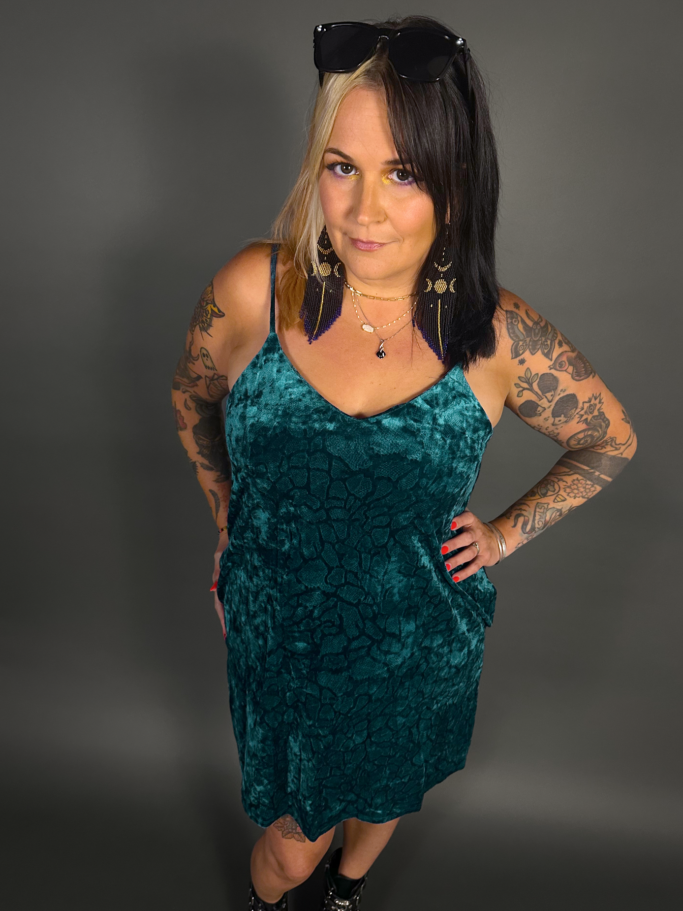 Woman wearing a teal velvet dress against a gray background