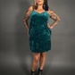 Woman wearing a teal velvet dress against a gray background