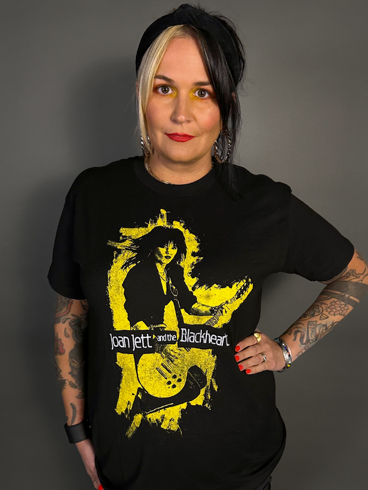 Person wearing a black t-shirt with a graphic design of Joan Jett and the Blackhearts on a gray background