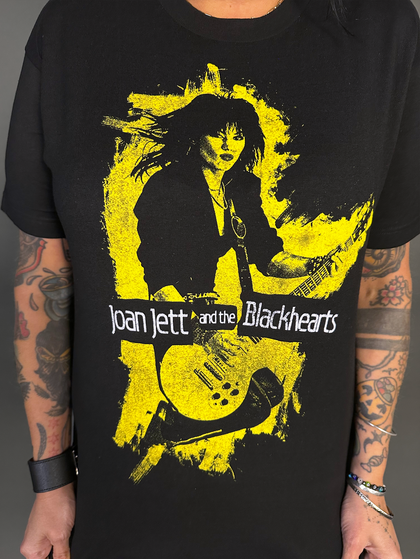 Black t-shirt with yellow graphic of Joan Jett and the Blackhearts on a dark background