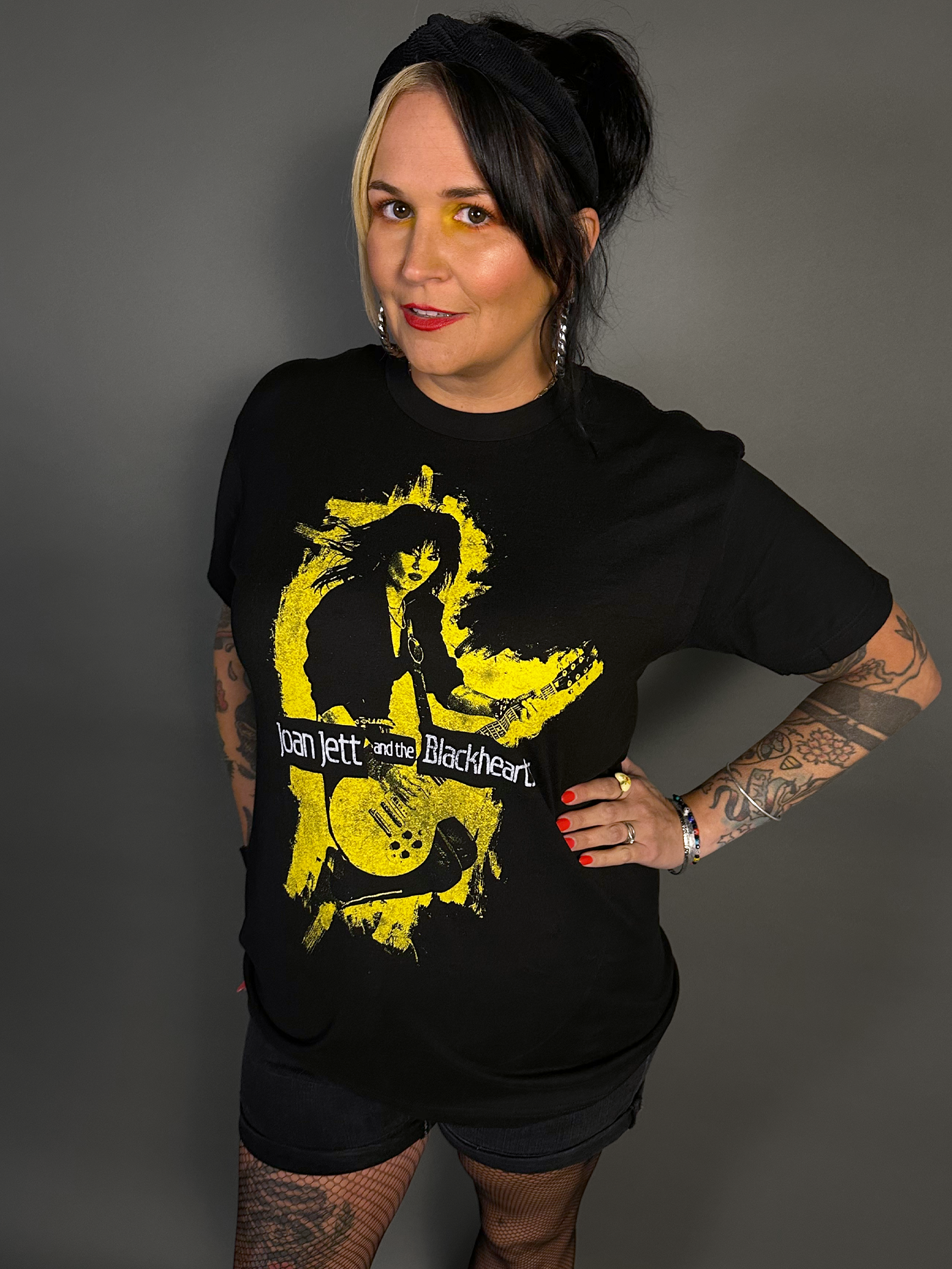 Woman wearing a black t-shirt with a yellow graphic design on a gray background