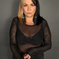 Woman wearing a black sheer top against a gray background