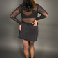 Woman wearing a black denim skirt and black top against a gray background