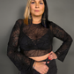 Woman wearing a black sheer top with spiderweb design against a gray background